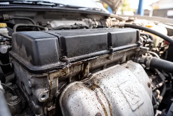 The seam where the valve cover meets the cylinder head, with dark oil seeping out and running down the side.